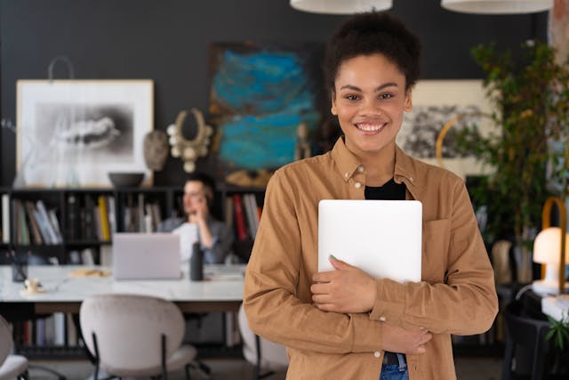 https://www.pexels.com/photo/a-woman-smiling-while-holding-a-laptop-6893892/ woman holding laptop / ethics hotline
